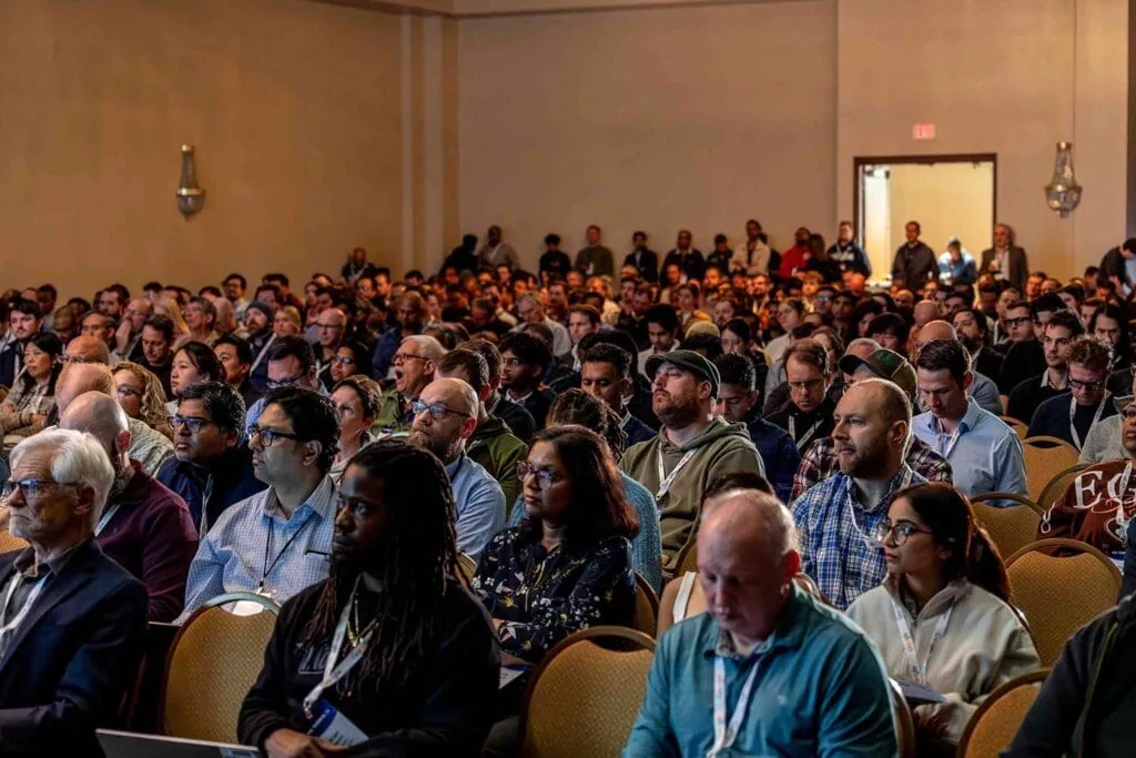A packed breakout session at All Things AI 2026, every seat taken and attendees standing along the back wall
