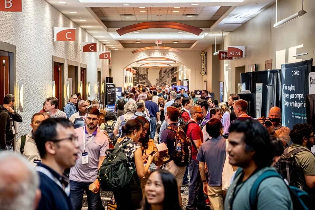Attendees talking in a crowded hallway outside the Grand Ballroom at All Things AI 2026