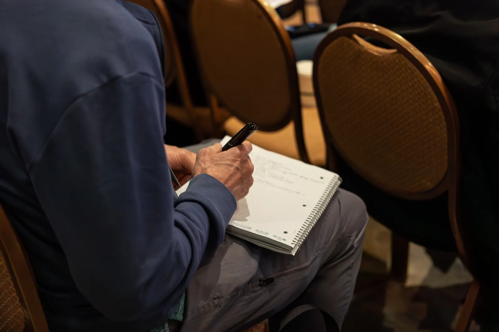 Close-up of an attendee taking handwritten notes during All Things AI 2026