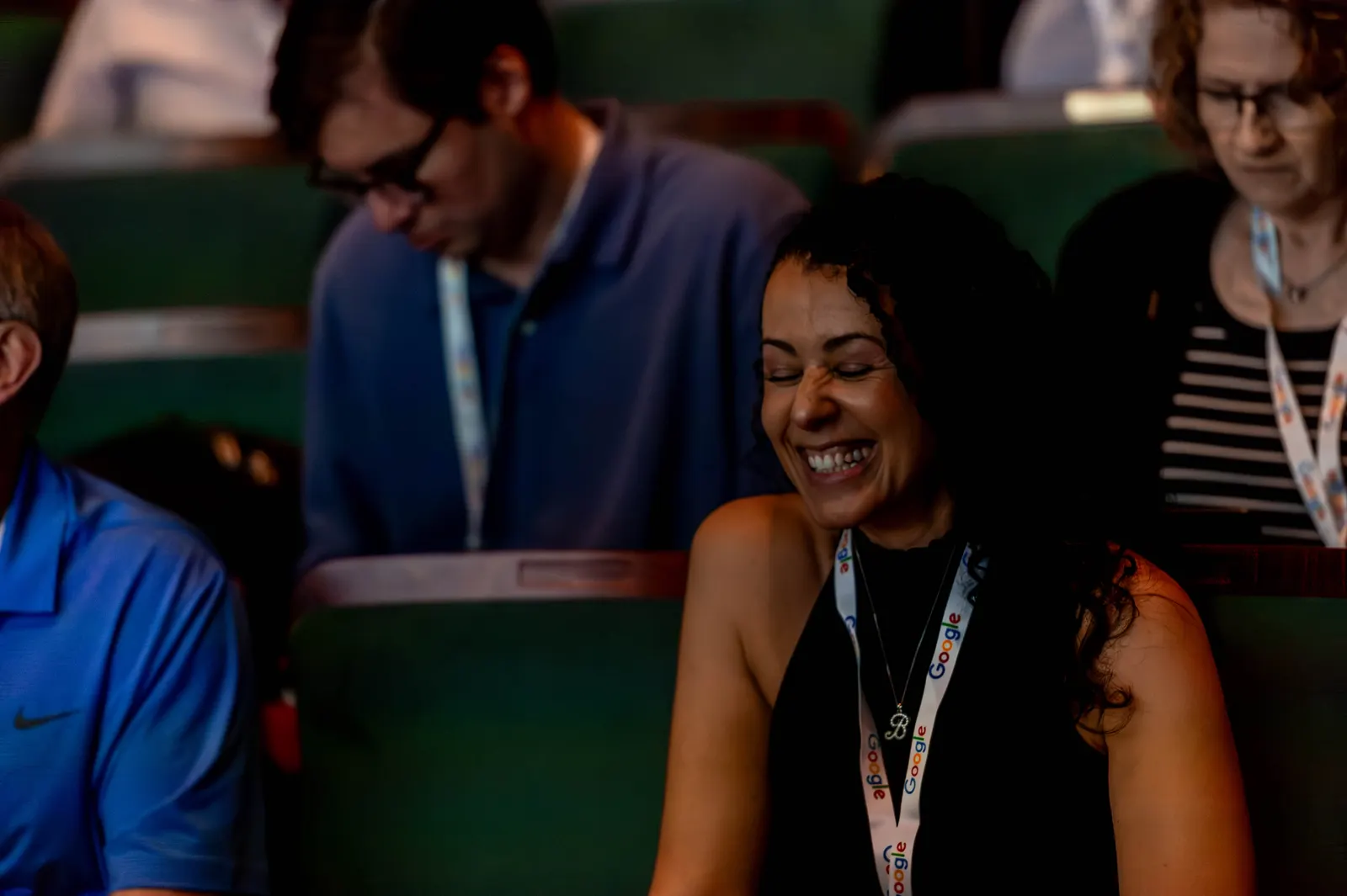 An attendee laughing in a green theatre seat during All Things AI 2026