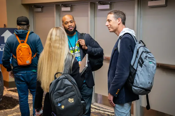 A small group of attendees smiling and talking in a conference hallway at All Things AI 2026