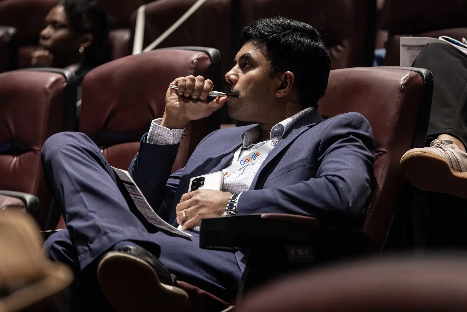 Close-up of an attendee watching a presentation from a theatre seat at All Things AI 2026