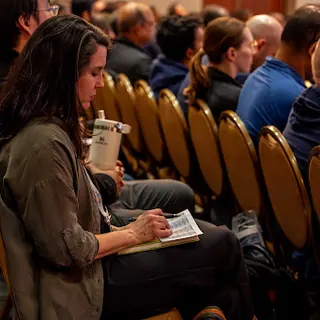 An attendee taking notes during an All Things AI session